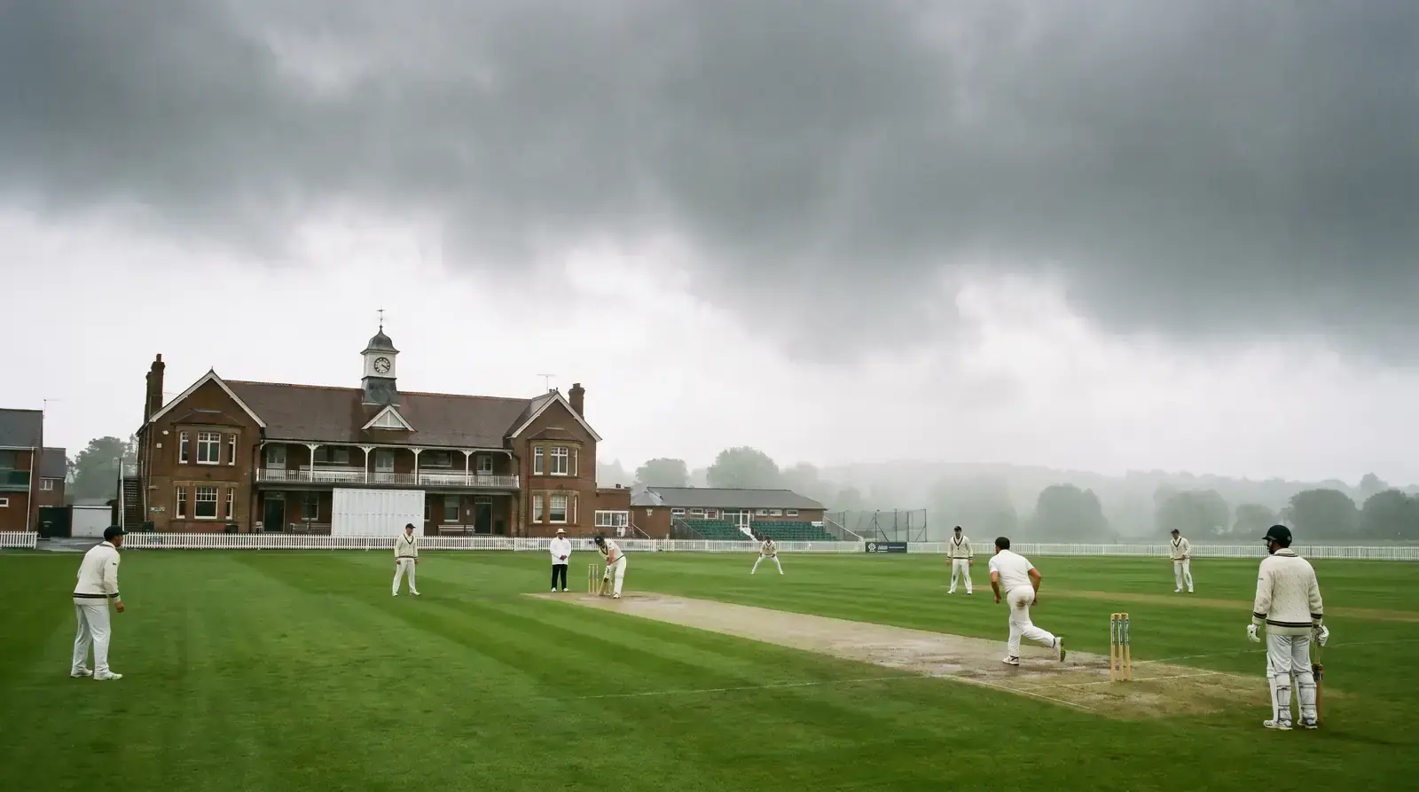 Cricket ball swinging through air under overcast English conditions with cloud cover visible